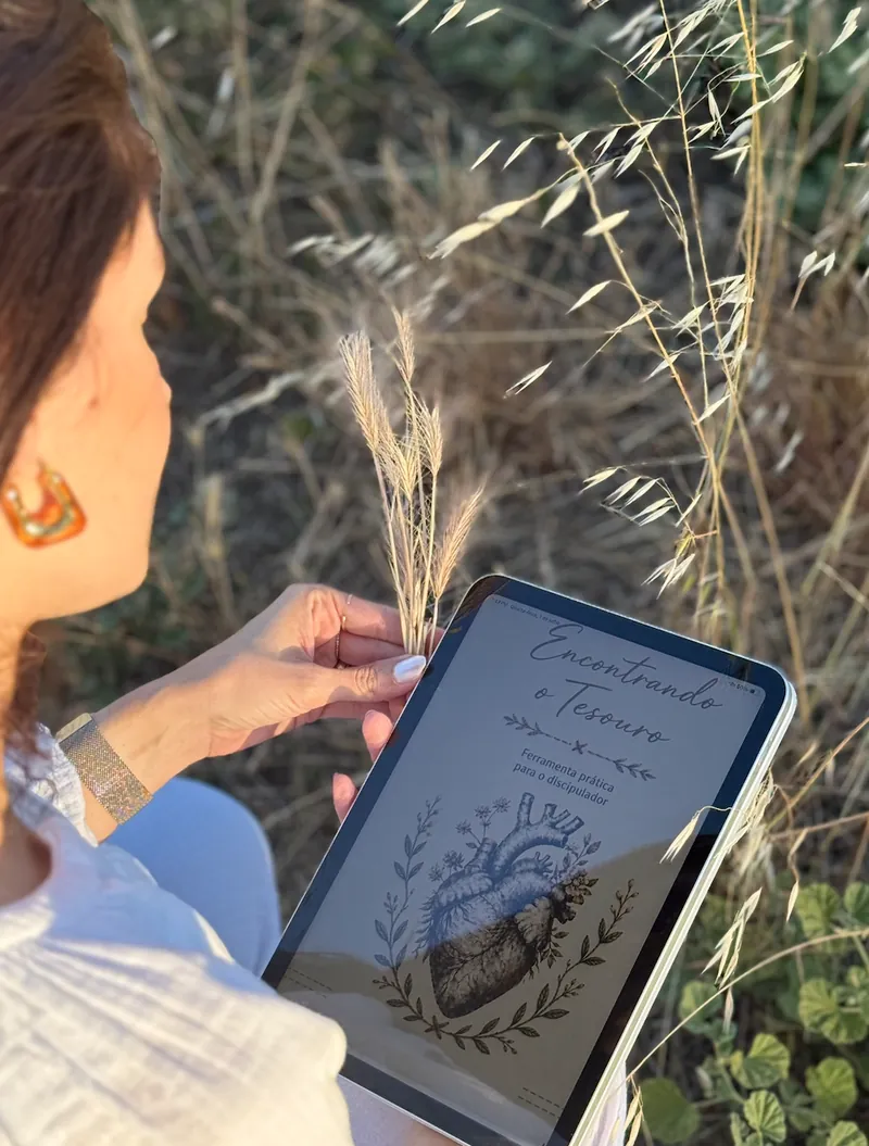 Deborah em um campo, segurando o iPad com o caderno digital