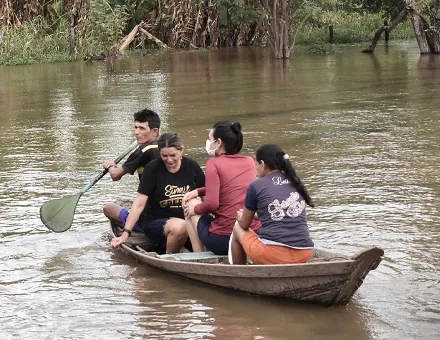 Equipe de missionários atravessando o rio em uma canoa