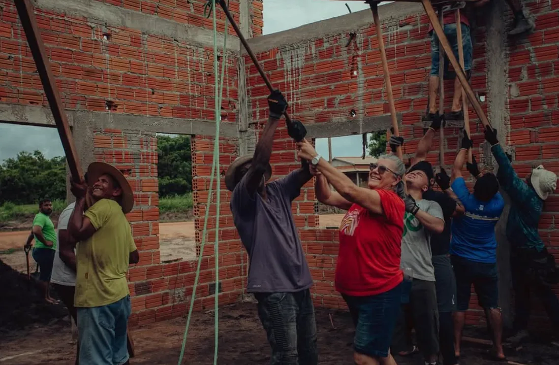 Grupo de voluntários erguendo a estrutura de uma igreja em construção