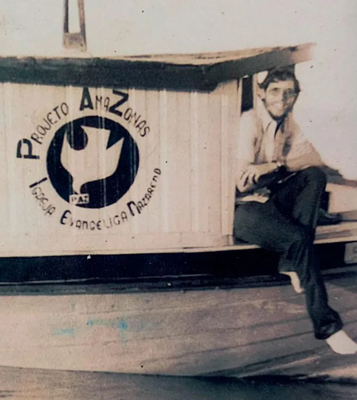 Fotografia antiga de um jovem sentado sobre o barco do Projeto Amazonas, missão iniciada em 1976